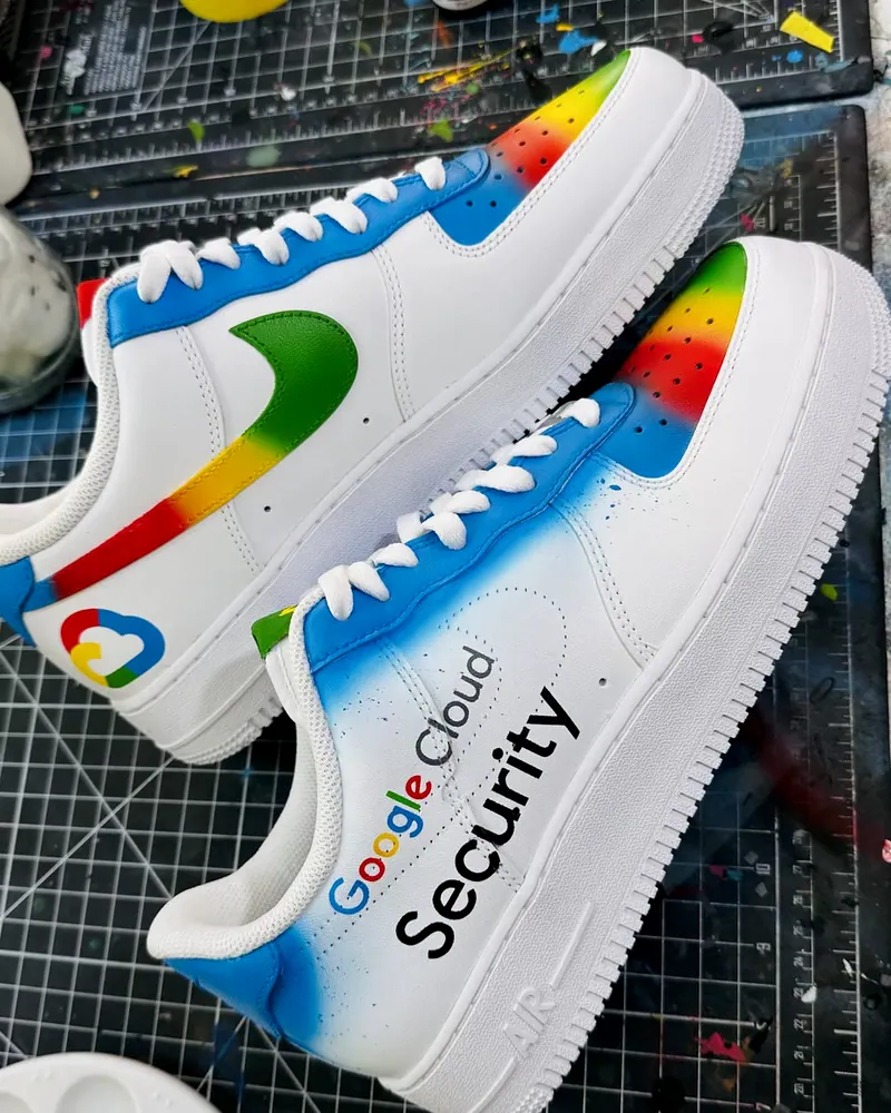 Par de tênis branco pintado à mão com a marca Google Cloud Security, o logo da nuvem e o swoosh nas cores do Google