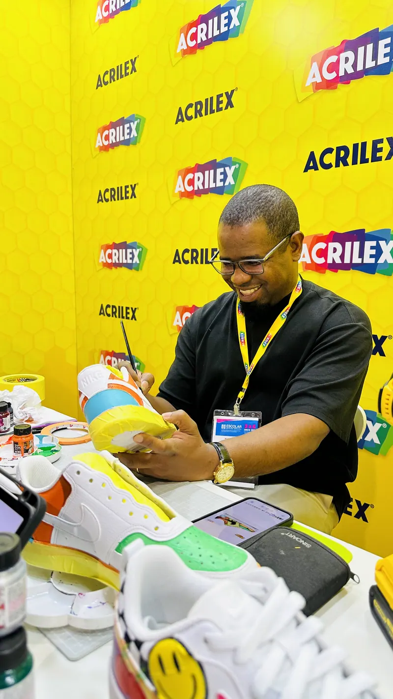 Thiago Peçanha pintando um tênis à mão no estande da Acrilex